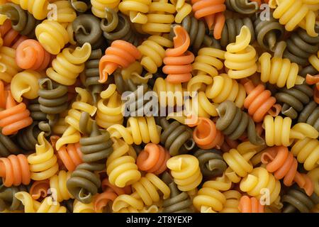 Fond de pâtes en spirale. Pâtes de différentes couleurs, vue de dessus, plat. Banque D'Images