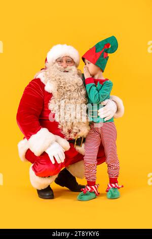 Mignon petit elfe dire souhait au Père Noël sur fond jaune Banque D'Images