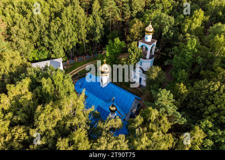 Vue aérienne d'une église orthodoxe avec des croix dorées et des dômes dans une zone forestière, une église dans un cimetière Banque D'Images