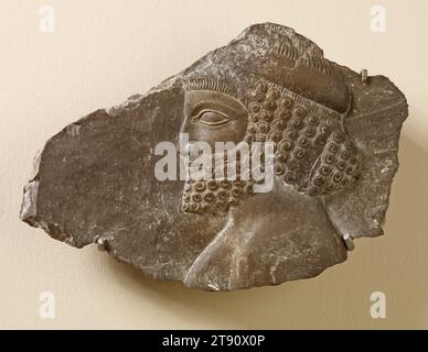 Fragment sculpté en relief de Persépolis, 486-465 av. J.-C., 6 1/4 x 9 3/8 x 1 3/4 po. (15,88 x 23,81 x 4,45 cm) (irrégulier), calcaire, Perse (Iran), 5e siècle av. J.-C., ce rare fragment de pierre portant la tête de profil sculpté d'un «délégué étranger» provient de l'escalier nord de la grande salle d'audience connue sous le nom d'Apadana à Persépolis; le magnifique complexe de palais cérémoniel des anciens rois perses, Darius I (522-486 av. J.-C.) et Xerxès I (486-456 av. J.-C.). Au temps de Xerxès Ier, l'immense empire perse comprenait Lydie, Babylone, Syrie, Palestine, Phénicie, Égypte, parties de l'Asie centrale Banque D'Images