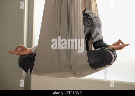 Homme méditant dans le hamac de yoga de mouche à l'intérieur, closeup Banque D'Images