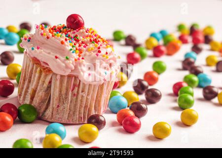 Cupcakes décorés de bonbons et de saupoudrages colorés avec des bonbons ronds dispersés sur le sol Banque D'Images