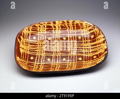 Plat à pain, c. 1820-1830, 3 1/8 x 21 3/16 x 15 3/4 po. (7,94 x 53,82 x 40,01 cm), Redware décoré de slip, Angleterre, 19e siècle, Redware décoré de motifs de slip était une partie importante de la tradition folklorique anglaise et américaine en céramique au cours des 18e et 19e siècles. La barbotine de couleur claire (argile diluée) a été peinte directement sur le corps en argile rouge. Des plumes et d'autres outils ont été glissés à travers le feuillet pour créer des motifs animés. Un regain d'intérêt pour la tradition des slips s'est produit au milieu du 20e siècle avec des céramistes tels que le potier anglais Michael Cardew Banque D'Images