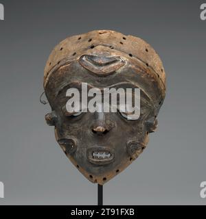 Masque, fin 19e-début 20e siècle, 9 5/8 x 7 13/16 x 3 7/8 po. (24,45 x 19,84 x 9,84 cm), Bois, fibres végétales, pigment, République démocratique du Congo, 19e-20e siècle, la plupart des masques du peuple Pende portent des noms spécifiques qui révèlent leur sexe, leur signification et leur fonction. Cependant, il est rarement possible d'identifier un masque Pende sans voir la robe et la danse qui l'accompagnent. À première vue, les caractéristiques faciales de ce masque semblent féminines, exprimant des idéaux de placidité et de maîtrise de soi. Pourtant, les hommes partagent aussi ces qualités Banque D'Images