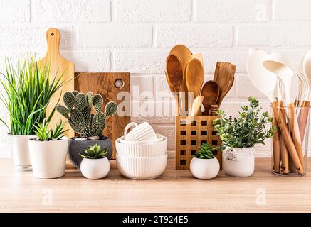 Beau fond de cuisine avec ensemble de planches à découper, cuillères en bois, bols. fleurs en pot . Vue avant. Cuisine écologique. Banque D'Images