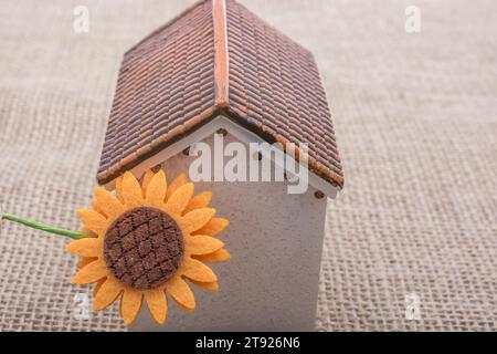 Fleur fausse par un modèle maison sur un fond de couleur marron Banque D'Images