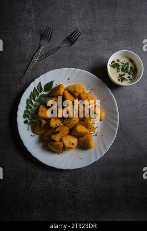 Vue du dessus de la nourriture du sud de l'Inde morceaux d'idli frits servis dans une assiette blanche. Banque D'Images