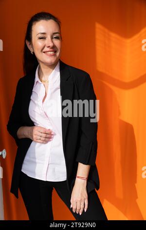 Belle femme en costume sombre d'affaires sur fond orange Banque D'Images