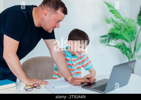 Homme aidant l'enfant à étudier à l'ordinateur Banque D'Images