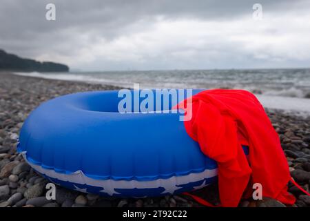 Bouée de sauvetage en caoutchouc bleu sur le rivage d'une plage de galets. Banque D'Images
