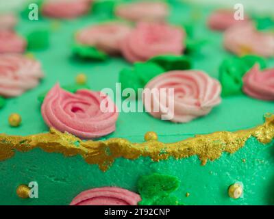 gâteau givré vert glaçage avec des roses de pâte de sucre et décoration de garniture de perles tout autour de la forme isolée sur le studio Banque D'Images