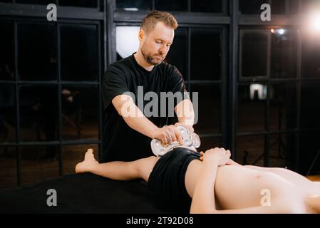 Massage avec une palette de massage spéciale, pétrissage des points de déclenchement dans l'abdomen, gros plan. Massage des lames. Vue latérale. Photo de haute qualité Banque D'Images