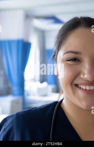 Demi-portrait de femme biracial heureuse médecin dans une chambre d'hôpital ensoleillée Banque D'Images