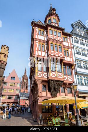 Clocher de la cathédrale vu de la place Römerberg dans la vieille ville de Francfort, bordé de maisons à colombages colorées et de cafés-terrasses. Banque D'Images
