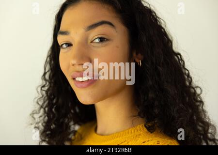 Portrait de femme biracial heureuse en chandail jaune à la maison Banque D'Images