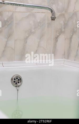 l'eau s'écoule du robinet remplissant le bain. remplissage de la baignoire avec de l'eau. bain avec de l'eau. vieux robinet de salle de bain Banque D'Images