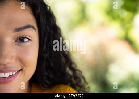 Demi portrait de femme biracial heureuse en pull jaune dans la nature ensoleillée avec espace copie Banque D'Images