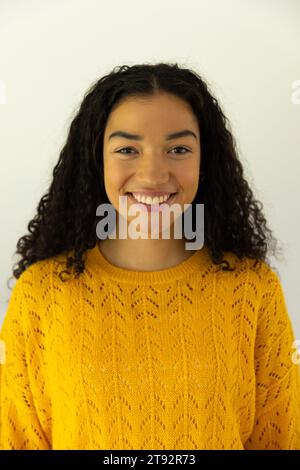 Portrait de femme biracial heureuse en chandail jaune à la maison Banque D'Images