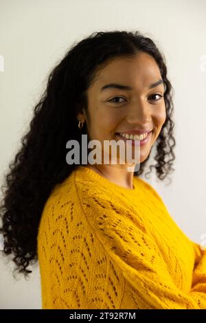 Portrait de femme biracial heureuse en chandail jaune à la maison. Mode de vie et vie domestique, inchangés. Banque D'Images