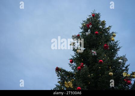 Plongez dans l'enchantement d'un arbre de Noël majestueux, debout et resplendissant avec des lumières rayonnantes, des ornements rouges, dorés et argentés Banque D'Images