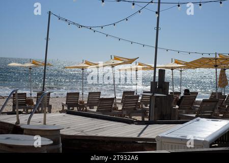 Bathers Beach, Fremantle, parasols jaunes et chaises longues en bois dans un soleil éclatant avec un océan bleu turquoise, des lumières de feston bleu ciel bleu bord de mer Banque D'Images