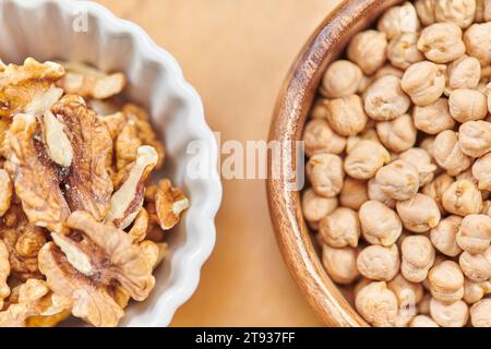 vue rapprochée de dessus des pois chiches et des noix dans des bols en bois et en céramique, concept de régimes à base de plantes Banque D'Images