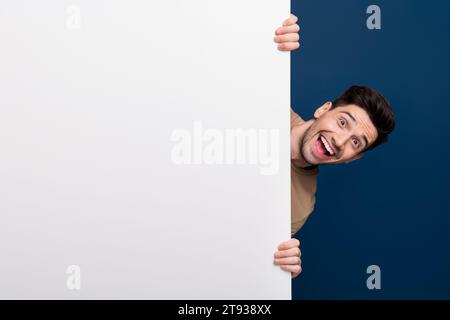 Photo de l'homme positif heureux porter des vêtements élégants look out affiche annonce vide espace vide isolé sur fond de couleur bleu foncé Banque D'Images