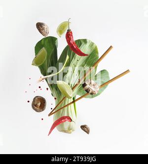Concept de nourriture asiatique avec des ingrédients volants : bok choy , baguettes, citron vert, shiitake, épices et piment sur fond blanc. Nourriture à lévitation. Vue avant Banque D'Images