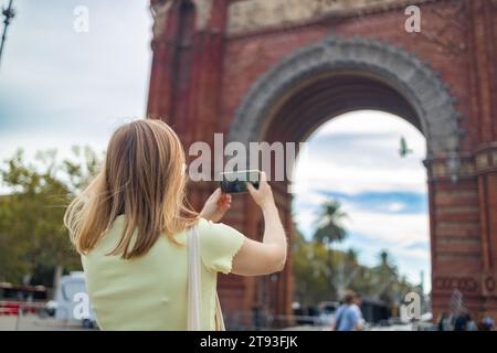 Femme faisant selfie contre l'architecture étonnante de la porte Arc de Triomf à Barcelone Banque D'Images