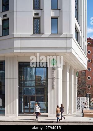 Vue le long de la façade du bâtiment avec entrée. Altus House, Leeds, Royaume-Uni. Architecte : O'Connell East Architects, 2022. Banque D'Images