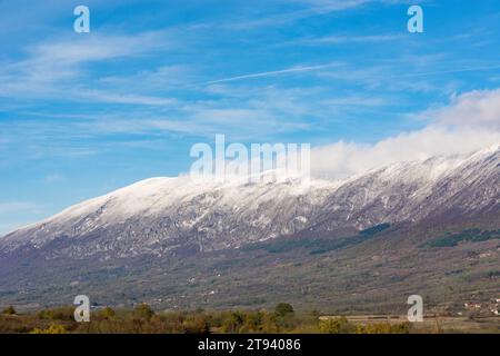 Paysage naturel avec une haute montagne sèche couronnée de neige et de nuages blancs contre un ciel d'automne clair, ensoleillé et frais Banque D'Images