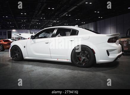 Une Dodge Charger Hell Cat blanche immaculée est exposée en évidence dans un salon de l'automobile, offrant un look élégant et élégant pour les gens à admirer Banque D'Images