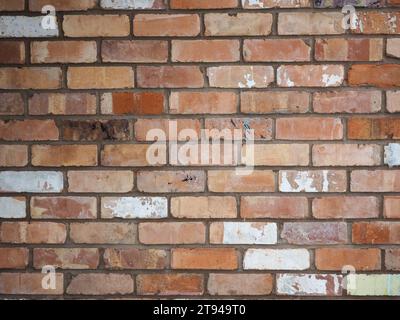 Fond de mur de briques vintage montrant des briques rouges victoriennes récupérées avec des restes de peinture ancienne Banque D'Images