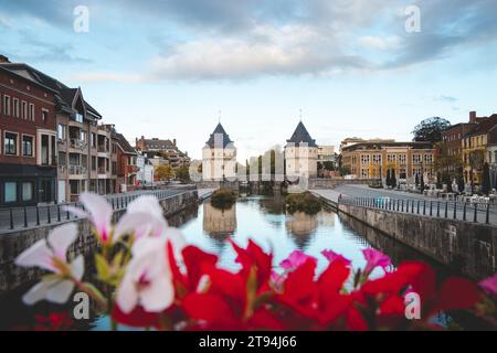 Centre-ville de Kortrijk avec deux tours historiques au bord de la rivière. Fleurs, rivière et bâtiments historiques. Ville belge dans le sud du pays. Banque D'Images