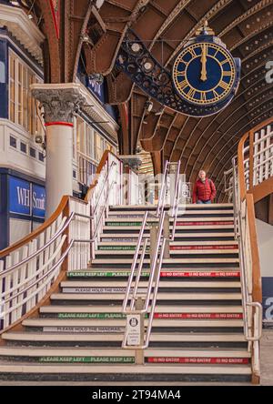 Un escalier situé sur un hall de gare mène à une grande horloge ornée. Une colonne et un magasin est d'un côté et au-dessus est un historique 19e EC Banque D'Images