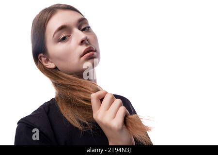 une fille de 15 ans aux cheveux bruns montre ses cheveux de près Banque D'Images