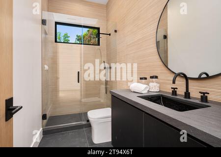 Cette salle de bains lumineuse et aérée est prête à être utilisée et appréciée, dotée d'une douche moderne et de surfaces impeccablement propres Banque D'Images