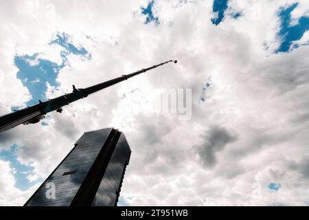 Une grande grue de camion bleue est prête à fonctionner sur un site près d'un grand bâtiment moderne. La plus grande grue de camion avec un berceau jaune pour résoudre c Banque D'Images