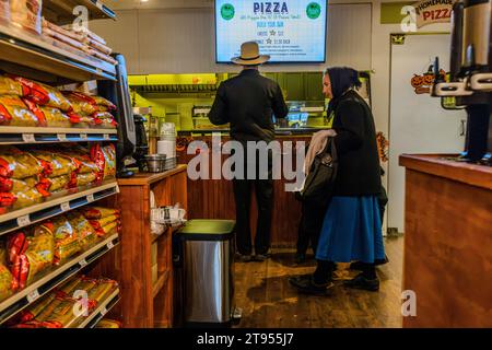 Les Amish font du shopping au Doud's Market, la plus ancienne épicerie d'Amérique. Le magasin a ouvert ses portes sur l'île Mackinac en 1884. Les Amish se sentent chez eux sur l'île sans voiture, qui semble être tombée hors du temps, tout comme le mode de vie Amish. Les Amish traditionnels et originaux sont populaires sur l'île Mackinac en raison de leur savoir-faire artisanal, par exemple dans la construction et la réparation de voitures. Avec leurs tenues, ils se démarquent difficilement dans le marché de Doud, la plus ancienne épicerie d'Amérique. Mackinac Island, Michigan, États-Unis Banque D'Images