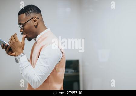 Photographié à travers un verre de noir, employé masculin ayant un appel téléphonique à la cabine téléphonique insonorisée pendant la pause au travail. Banque D'Images