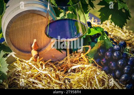 verre à vin et fût, raisins noirs et paille Banque D'Images