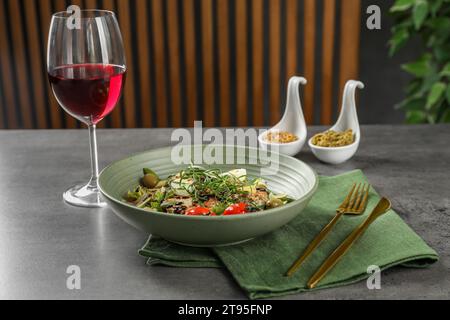 Plat savoureux avec estragon, vinaigrettes et verre de vin servi sur une table grise Banque D'Images