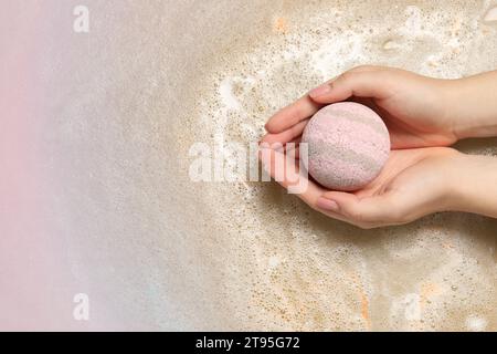 Femme tenant une bombe de bain sur l'eau avec de la mousse, vue de dessus. Espace pour le texte Banque D'Images