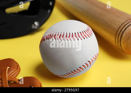 Balle de baseball et batte sur fond jaune, gros plan Banque D'Images