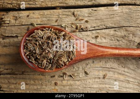 Cuillère de graines d'aneth sèches sur la table en bois, vue de dessus Banque D'Images