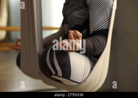 Homme méditant dans le hamac de yoga de mouche à l'intérieur, closeup Banque D'Images