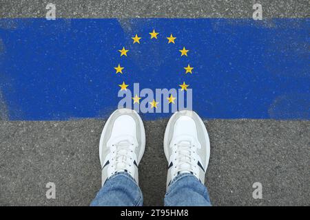 Immigration. Homme debout sur l'asphalte près du drapeau de l'Union européenne, vue de dessus Banque D'Images