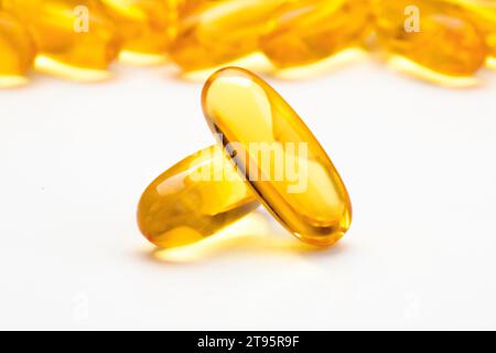 Capsules de gel souple à l'huile de poisson dispersées sur une table blanche, Focus sur le premier plan. Banque D'Images