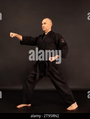 Portrait de maître de sensei aikido avec ceinture sensei noire en kimono taekwondo sur fond noir. Kimono traditionnel samouraï hakama. Mode de vie sain Banque D'Images