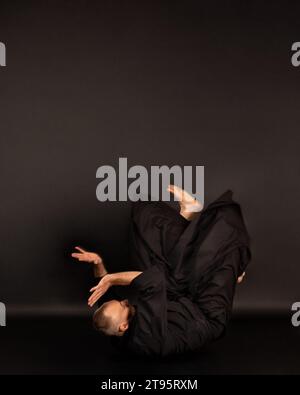 Portrait de maître de sensei aikido avec ceinture sensei noire en kimono taekwondo sur fond noir. Kimono traditionnel samouraï hakama. Mode de vie sain Banque D'Images